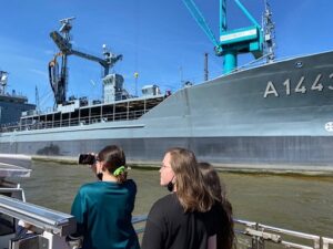 Schüler vor Militärschiff im Hamburger Hafen