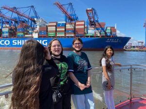 Schüler vor Containerschiff auf Barkasse
