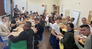 ATW_Kubaner:innen sitzen gemeinsam im Klassenraum und essen