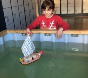 Schülerin lässt selbstgebautes Schiff auf das Wasser gleiten