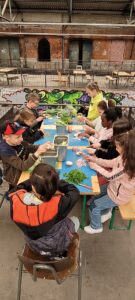 Kinder sitzen an Bänken und schnippeln Gemüse in der Alten Gleishalle