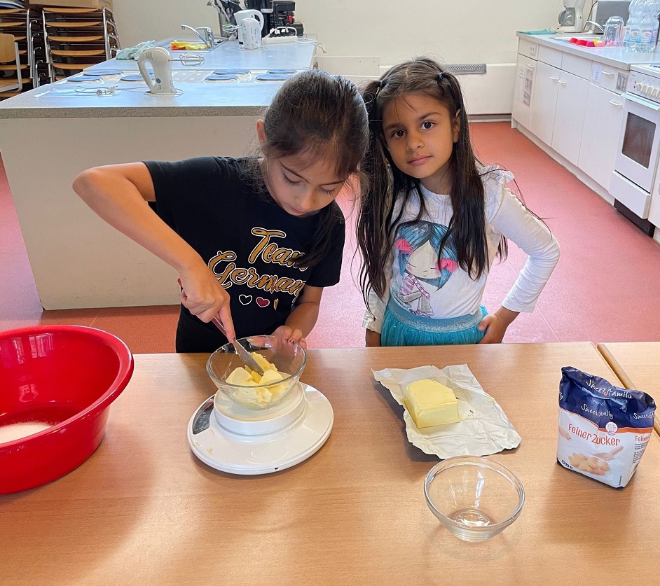 Zwei Mädchen stehen in der Küche und schneiden Butter in Stücke