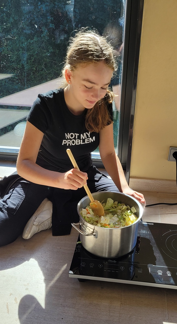 Ein Mädchen sitzt am Boden und kocht Suppe in der Kinder Forscher Werkstatt