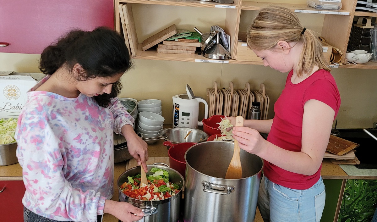 Zwei Mädchen stehen am Herd in der Kinder Forscher Werkstatt und kochen Suppe